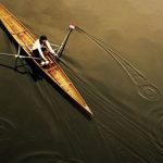 An overhead view of a sculler rowing on the water